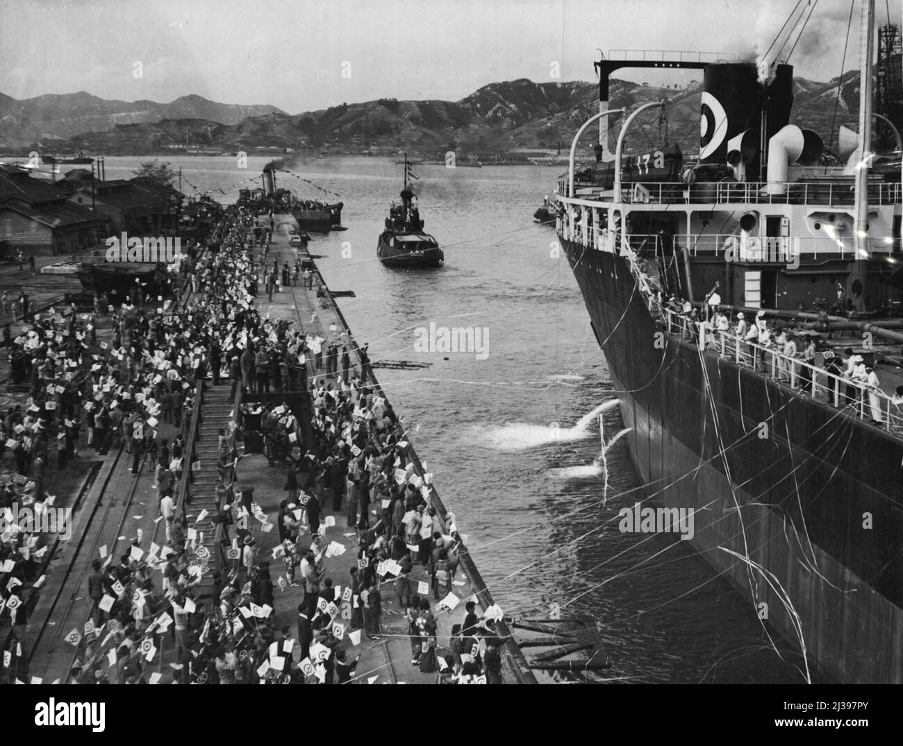 Nach dem Umbau in Kure Docks fährt der japanische Öltanker 'Gyokuei Maru' nach Persien, um Öl zu laden. Sie wird dann zur Antarktis fahren, wo sie als Versorgungsschiff für die japanische Walfangflotte fungieren wird. Menschenmengen auf dem Kai winken Fahnen und halten Luftschlangen fest, während das Schiff anfängt sich zu bewegen. Gebete wurden für ihre sichere Rückkehr angeboten, beladen mit dem dringend benötigten Walöl und Fleisch. 8. Dezember 1949. Stockfoto