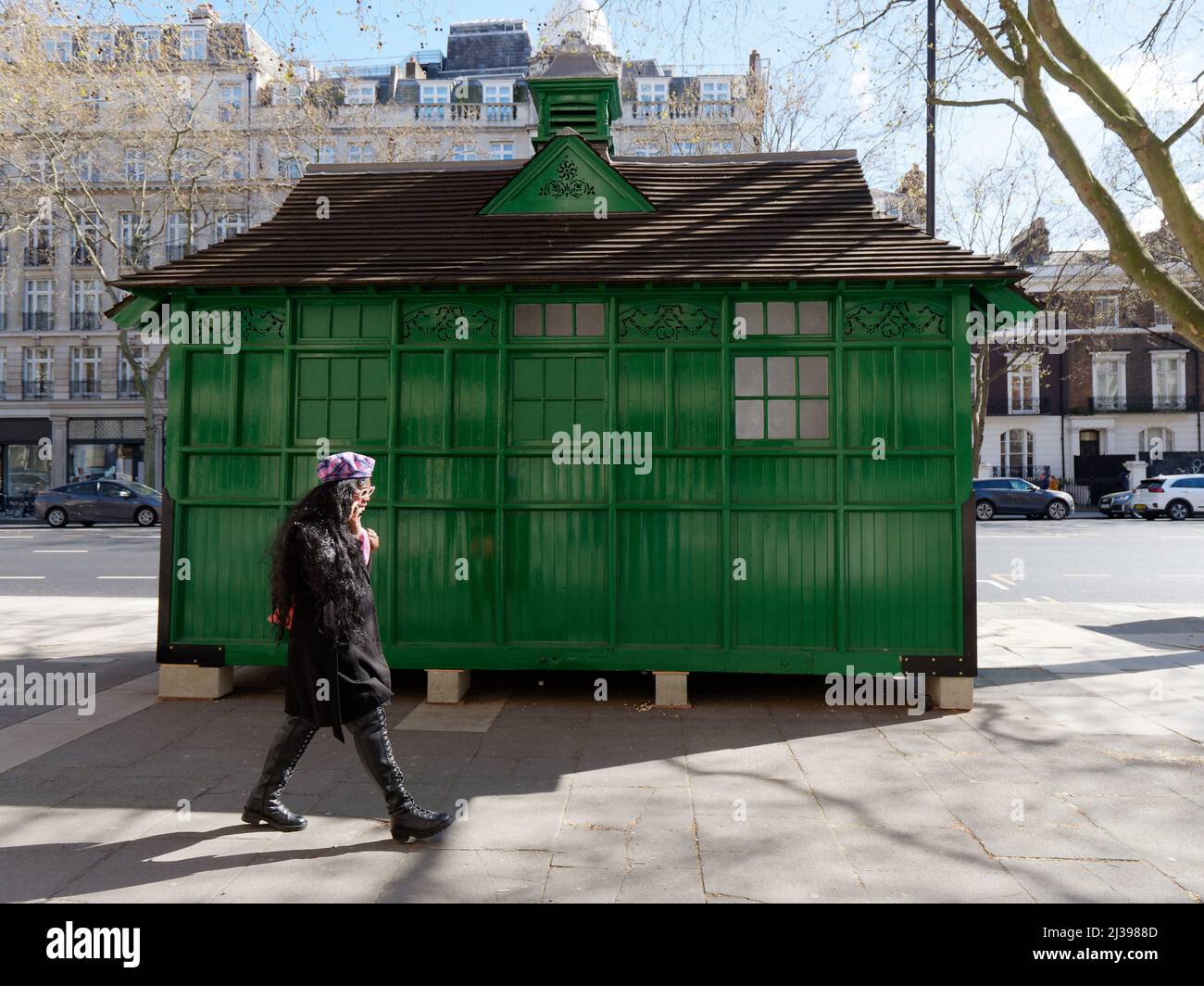 Wooden Green Shed oder Hütte genannt Cabmen Shelters in der Knightsbridge Gegend. Fußgänger laufen mit einer Sonnenbrille. Stockfoto
