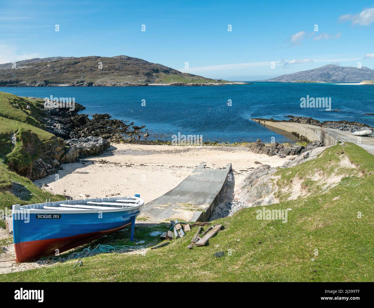 Kleines Boot auf der Helling und am Anlegesteg in Port A' Tuath, Hushinish mit Caolas an Scarp und der Insel Scarp dahinter, Isle of Harris, Schottland, Großbritannien Stockfoto