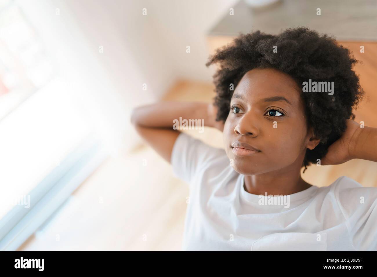 Junge afrikanische Frau, die sich auf einem Stuhl in der Küche entspannt Stockfoto