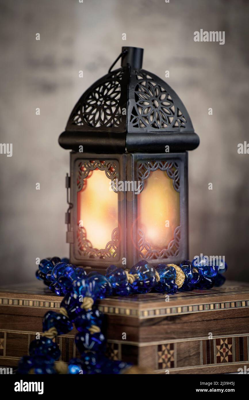 Ramadan Laterne erhellen und ein Blauer arabischer Rosenkranz über einer Arabeske Box in einer Vintage-Stimmung oder Umgebung . Stockfoto