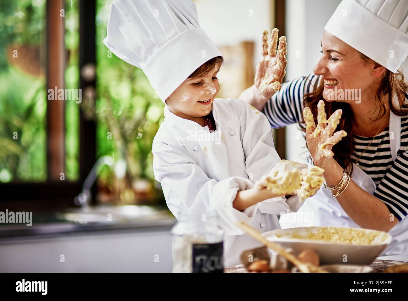 Bringen Sie es für die Teamarbeit mit. Aufnahme einer Mutter und ihres Sohnes beim Backen in der Küche. Stockfoto