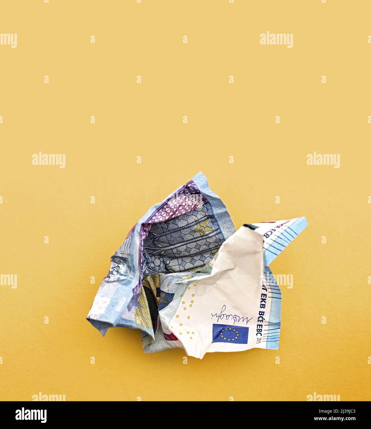 Knitterter Geldschein. 20 Euro Banknote. Geldverschwendung auf gelbem Hintergrund Stockfoto