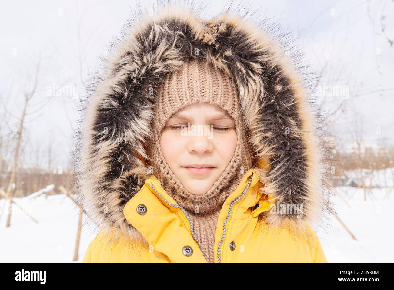 Porträt eines Mädchens mit geschlossenen Augen in Winterkleidung. Stockfoto