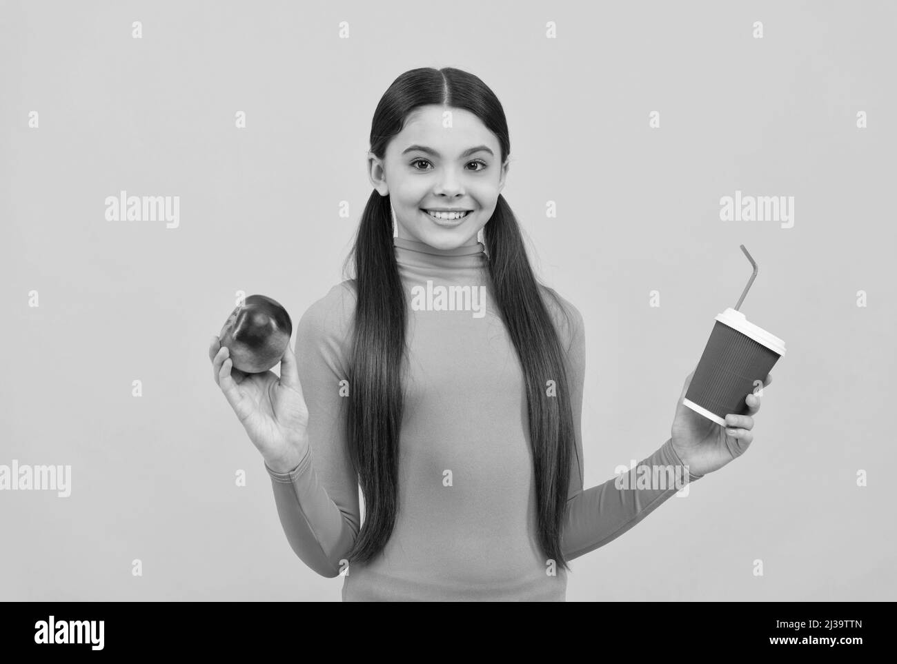 Happy teen Mädchen mit Take Away Kaffeetasse und Apfel auf gelbem Hintergrund, Mittagessen Stockfoto