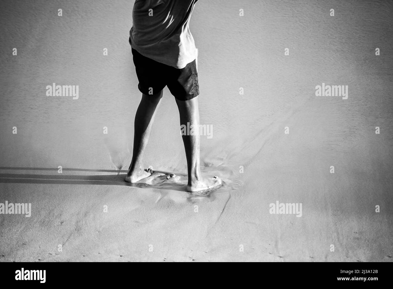 Unterer Teil einer Person, die auf dem Strandsand steht. Salvador Stadt, Bahia Staat, Brasilien. Stockfoto