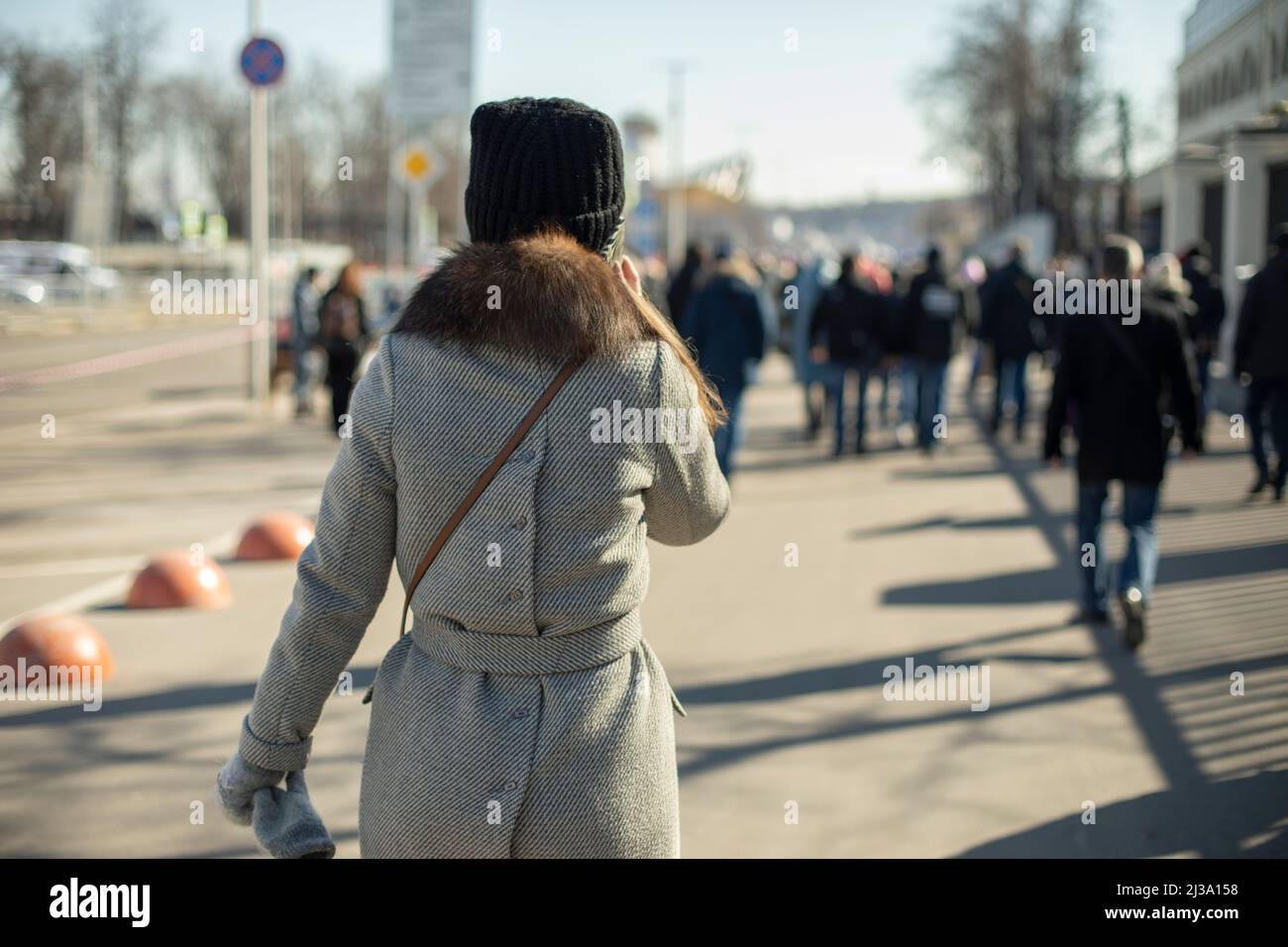 Mädchen läuft durch die Stadt. Frau auf der Straße. Federkleidung auf Person. Zu Fuß entlang der Straße. Viele Leute. Stockfoto