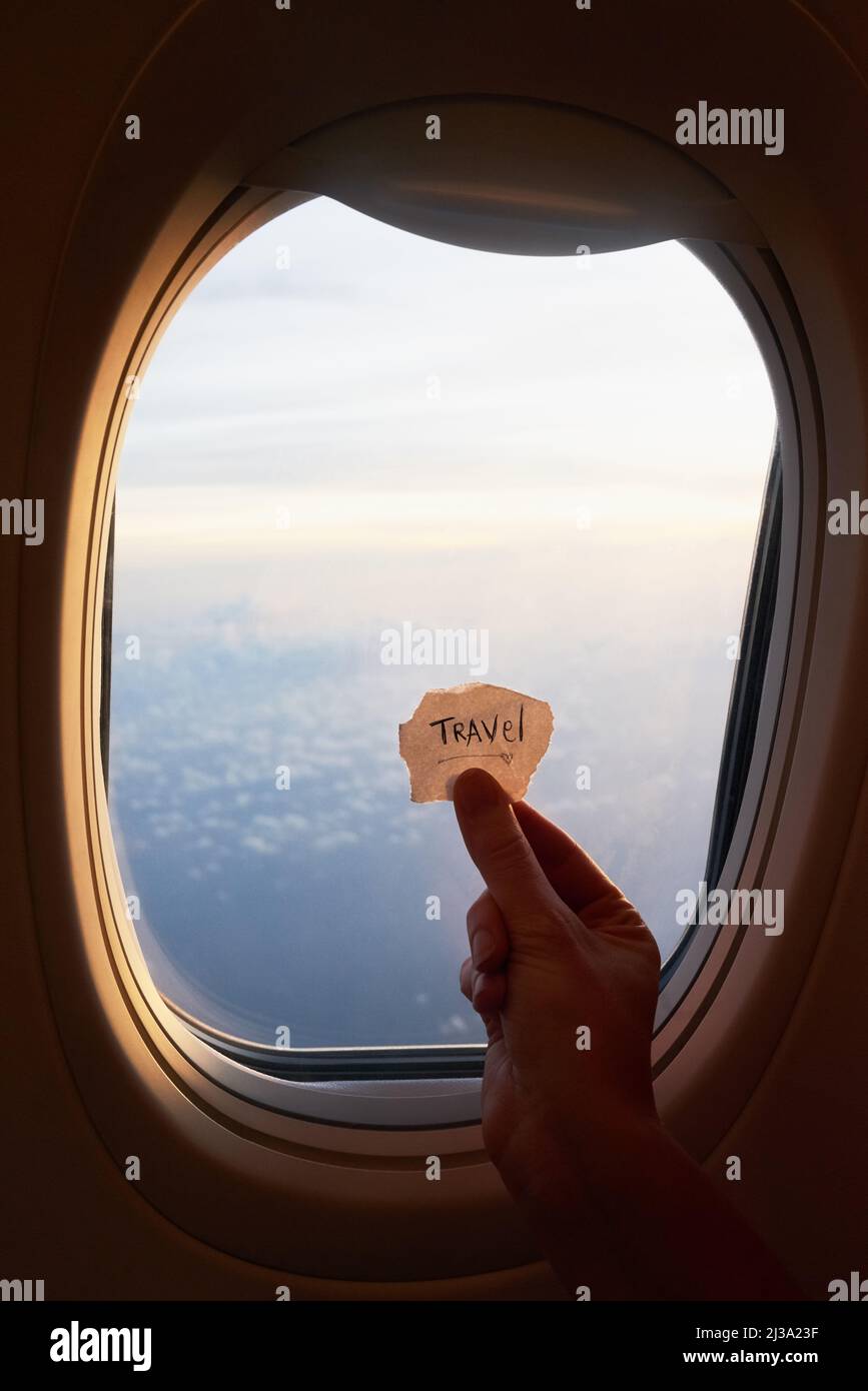Lebe dein Traumleben. Aufnahme einer Hand einer nicht erkennbaren Person, die eine Notiz gegen das Fenster eines Flugzeugs hält. Stockfoto