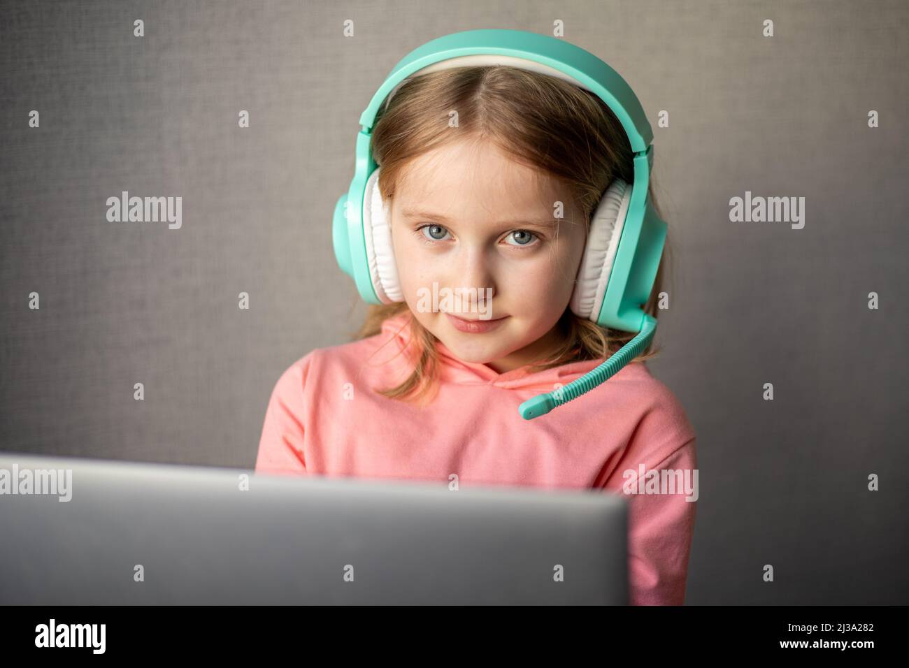 Mädchen, 7-8 Jahre alt, die Kopfhörer trägt, lernen, Online-Webinare, Webcast anzusehen, Fernlehrgang auf dem Laptop zu sehen oder Videoanruf an die Lehrerin zu verwenden Stockfoto