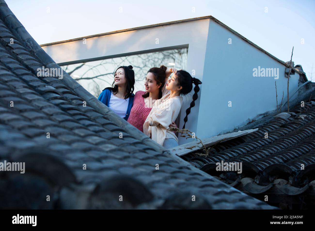 Chinesische junge Damen genießen die traditionelle architektonische Landschaft von Pekings Siheyuan an einem raumhohen Fenster - Stock Photo Stockfoto