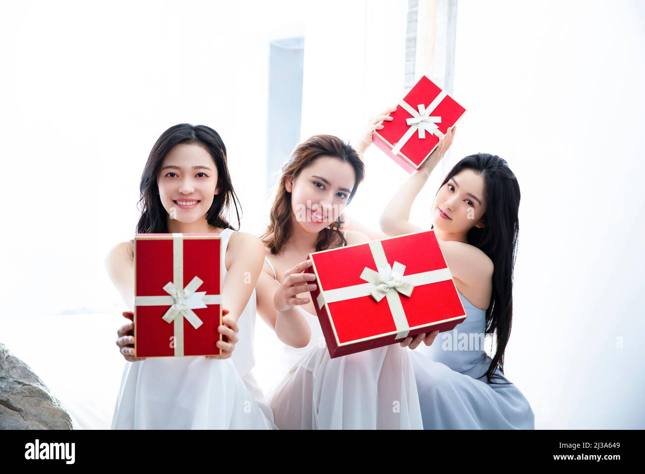 Modisch gekleidete junge Frauen mit roten Geschenkschachteln - Stock Foto Stockfoto