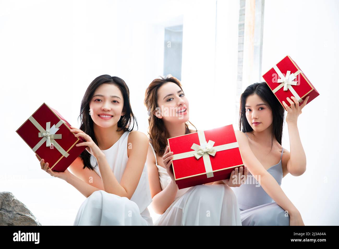 Modisch gekleidete junge Frauen mit roten Geschenkschachteln - Stock Foto Stockfoto