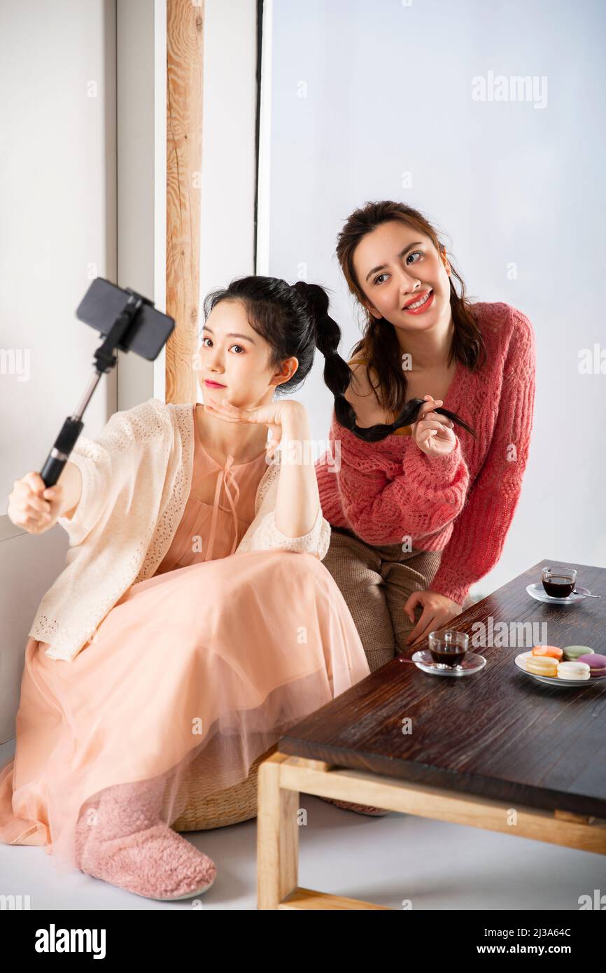 Modische junge chinesische Frauen, die zur Teezeit ein Selfie mit einem Selfie-Stick machen - Stockfoto Stockfoto