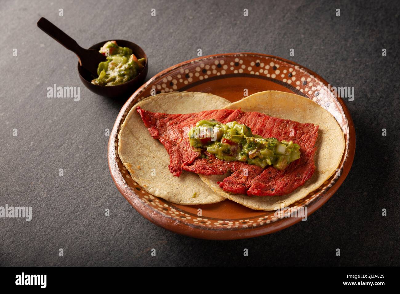Tacos de Cecina Enchilada con Guacamole. Gesalzenes, sonnengetrocknetes Schweinefleisch oder Rindfleisch, gewürzt mit verschiedenen Gewürzen und Chilischoten, in der Regel in Tacos gegessen Stockfoto