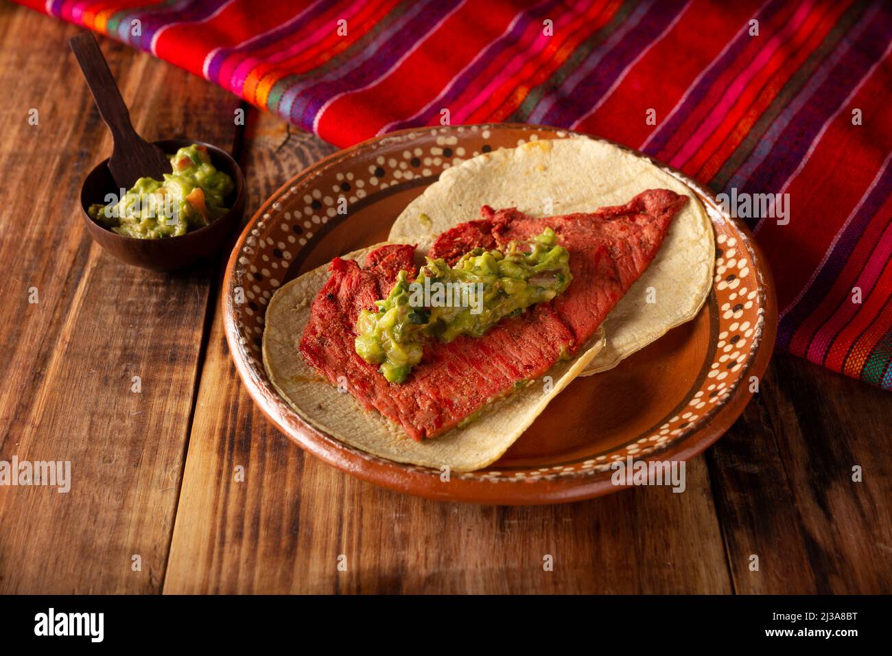 Tacos de Cecina Enchilada con Guacamole. Gesalzenes, sonnengetrocknetes Schweinefleisch oder Rindfleisch, gewürzt mit verschiedenen Gewürzen und Chilischoten, in der Regel in Tacos gegessen Stockfoto
