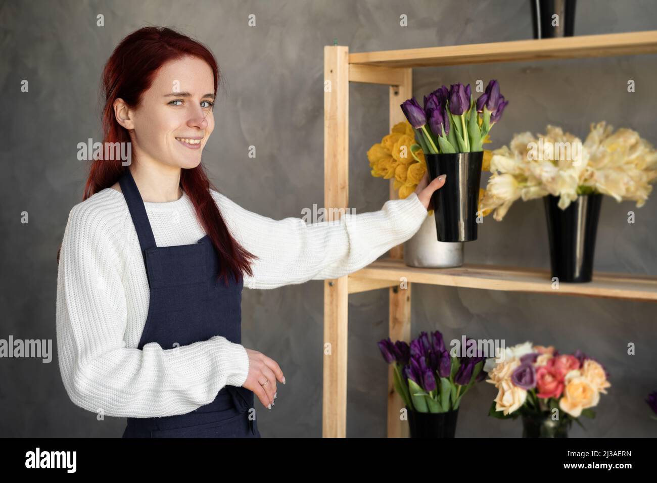Kleines Unternehmen. Frau Floristin in Blumenladen in der Nähe Vitrine mit Tulpen. Floral Design Studio, Produktion von Dekorationen und Arrangements. Blume Stockfoto