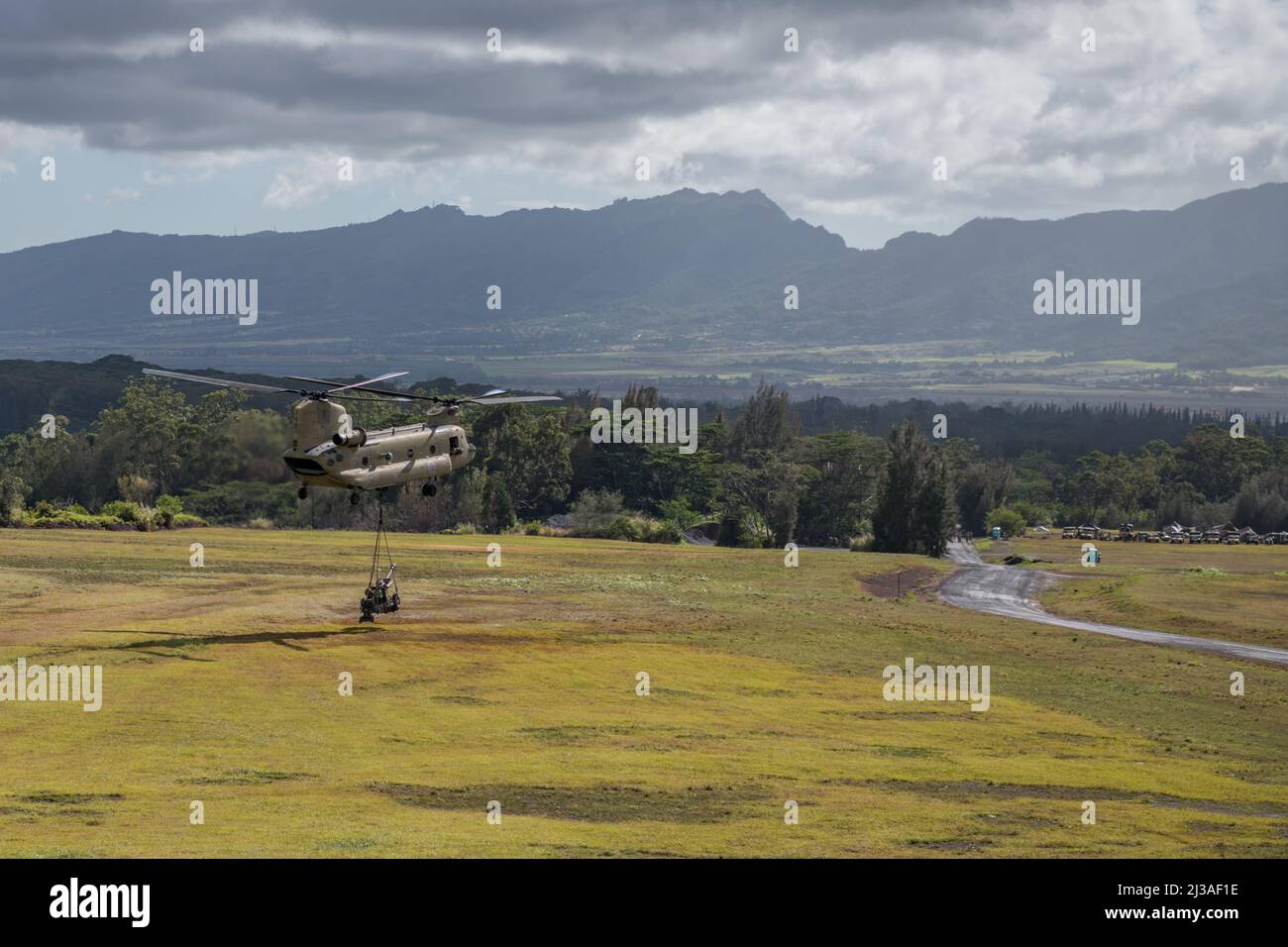 A Hawaii Army National Guard (HIARNG) CH-47 Chinook von Company B, 2. Bataillon, 211. Aviation Regiment, senkt eine M119A3 Haubitze auf Schofield Barracks, Hawaii, 2. April 2022. HIARNG-Soldaten des Bataillons 1., des Artillerieregiments 487. und des Kampfteams der Infanterie-Brigade 29. führten das Luftangriffsschlingentraining im Rahmen einer Zertifizierung für batteriegewehrte Waffen durch. (USA Foto der Armee-Nationalgarde von Sgt. John Schoebel) Stockfoto