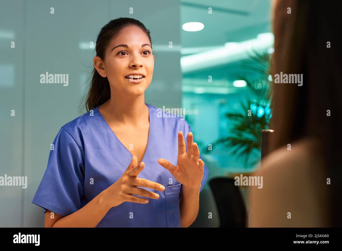 Erläuterung der medizinischen Abdeckung. Aufnahme einer jungen Krankenschwester, die mit ihrer Patientin in der Klinik über einen Eingriff diskutiert. Stockfoto