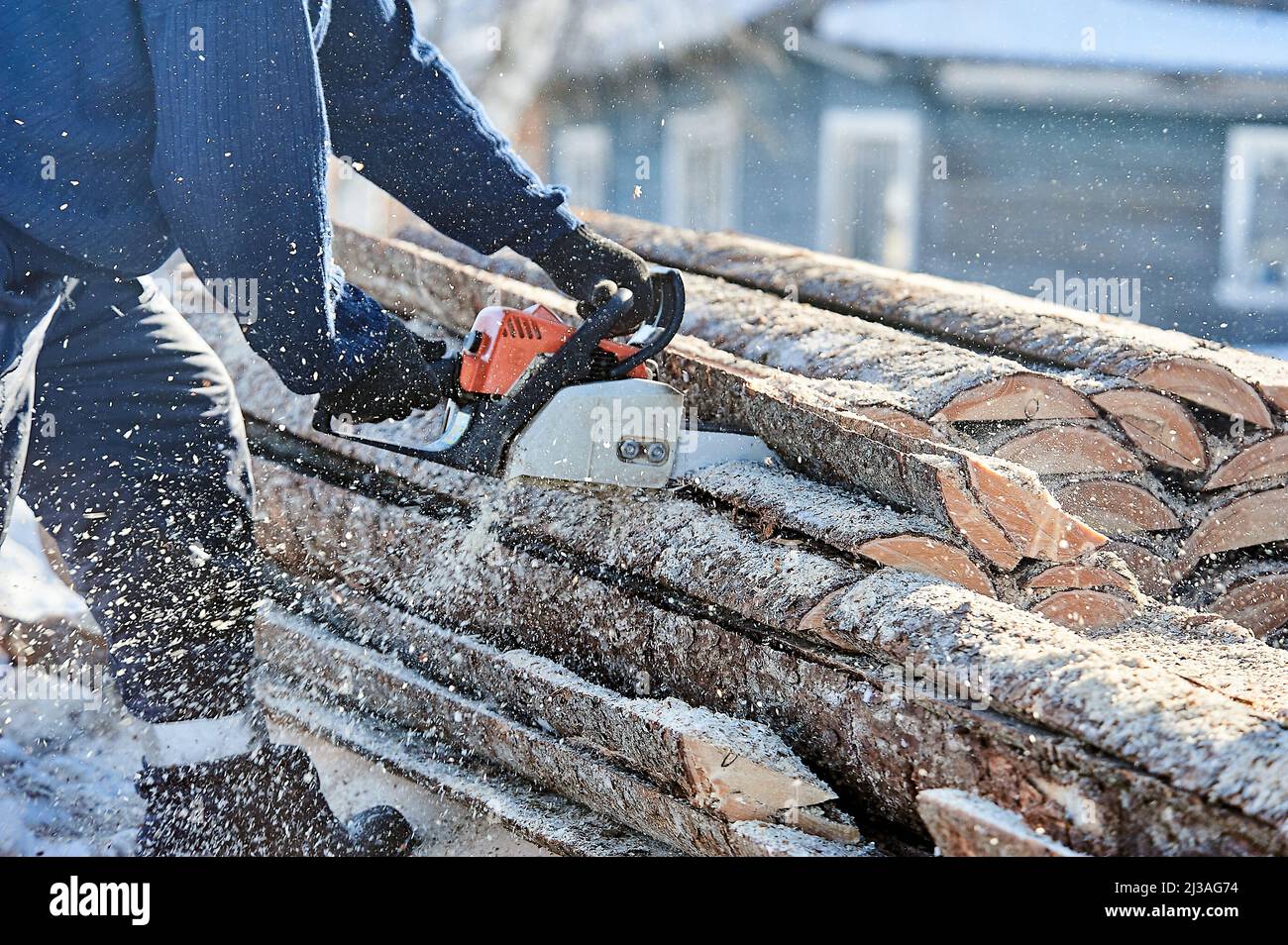 Sägen von Holz mit einer Kettensäge für den Ofenofen an der frischen Luft Stockfoto