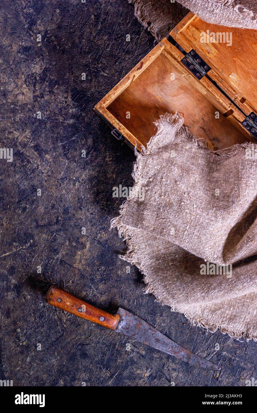 Vintage Metzgermesser und alte Holzkiste auf Steinküchenoberfläche. Draufsicht mit selektivem Fokus Stockfoto