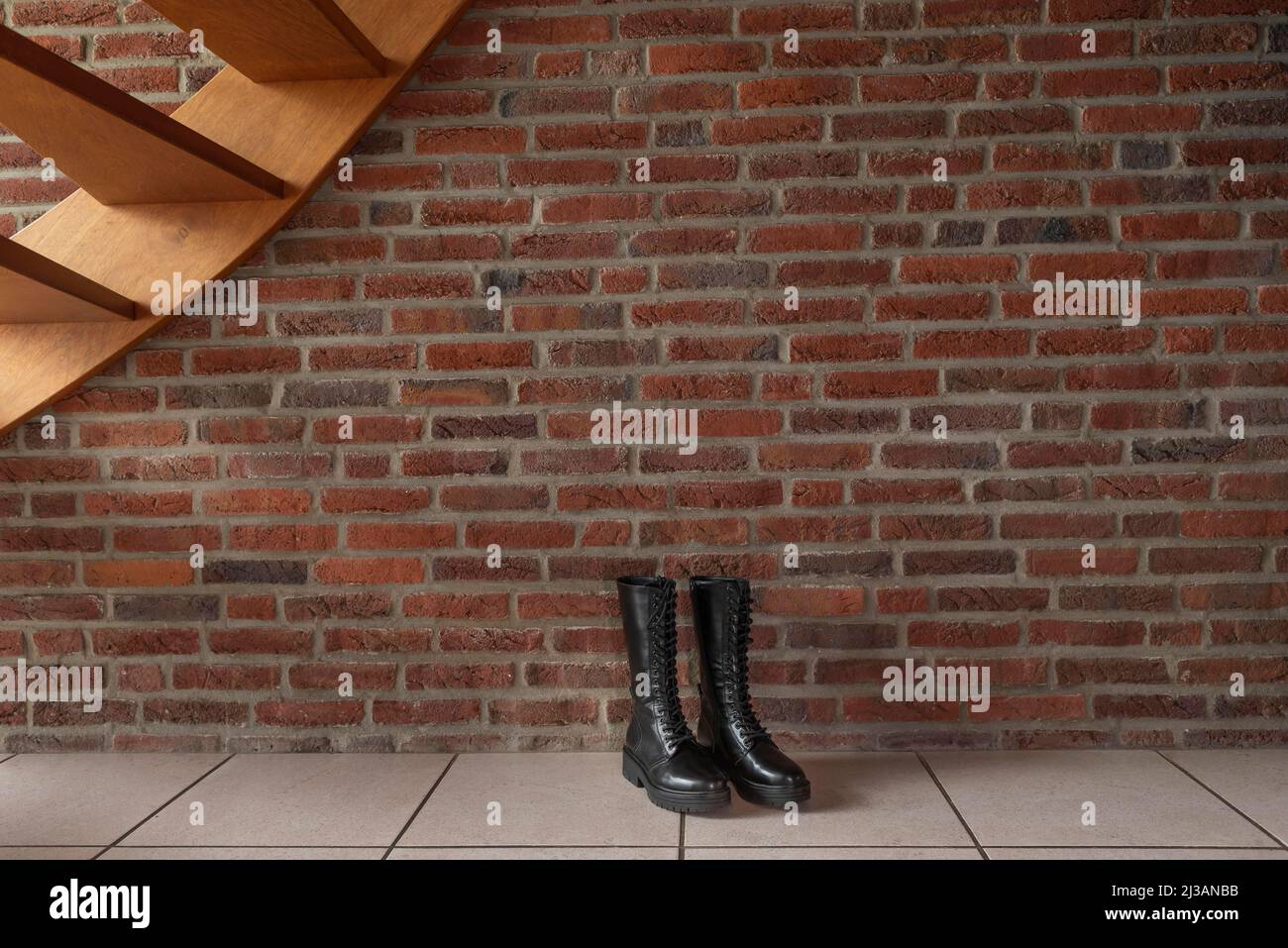 Schwarze Schuhe unter der Treppe vor dem Hintergrund einer Backsteinmauer Stockfoto