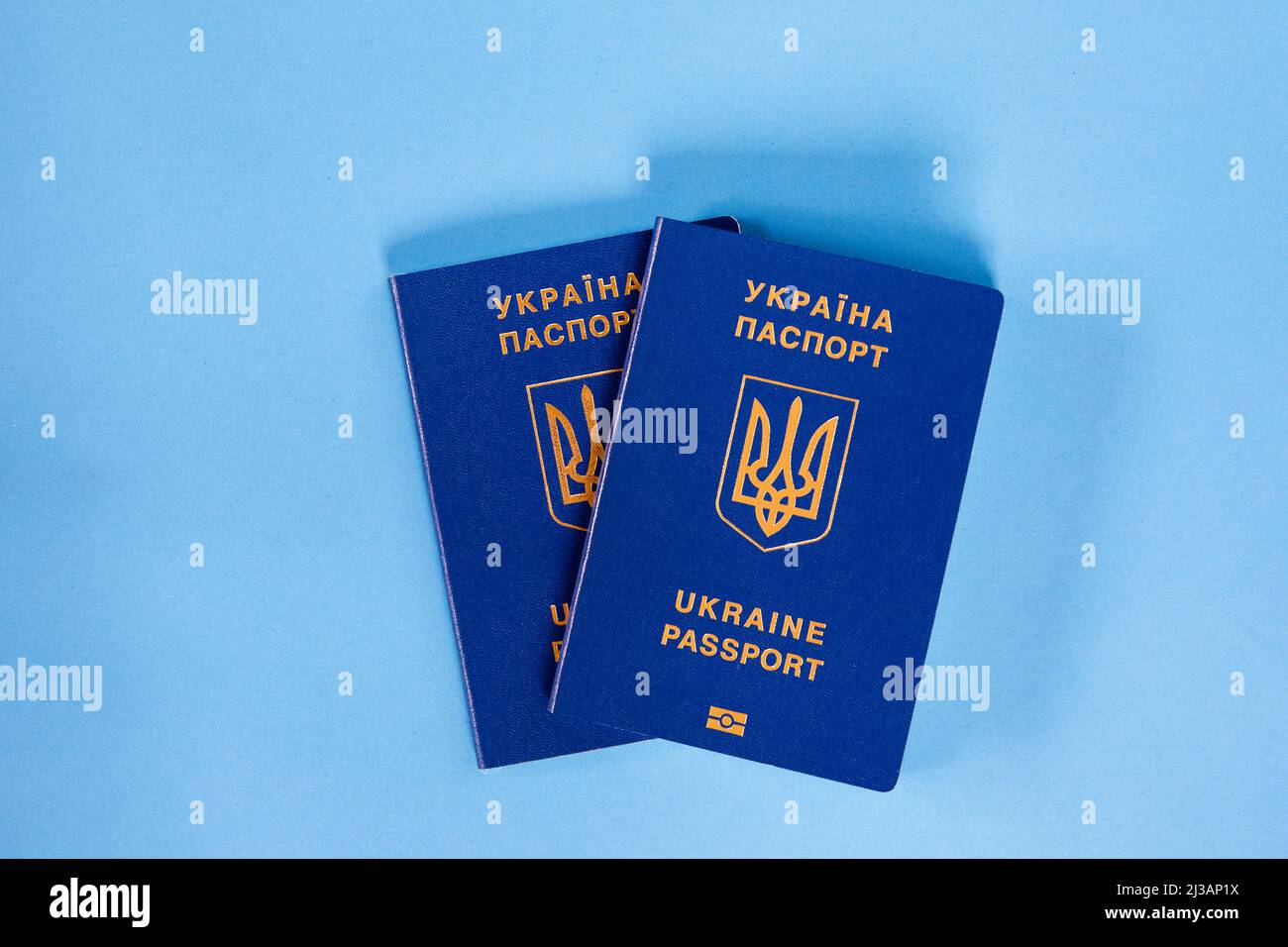 Zwei biometrische Pässe ukrainischer Bürger auf blauem Hintergrund. Das Konzept der Migration der Ukrainer Stockfoto