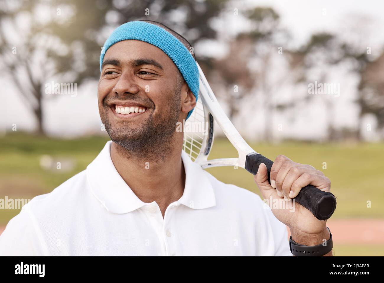 Das Lächeln eines Gewinners. Aufnahme eines hübschen jungen Mannes, der allein draußen steht und mit einem Tennisschläger posiert. Stockfoto