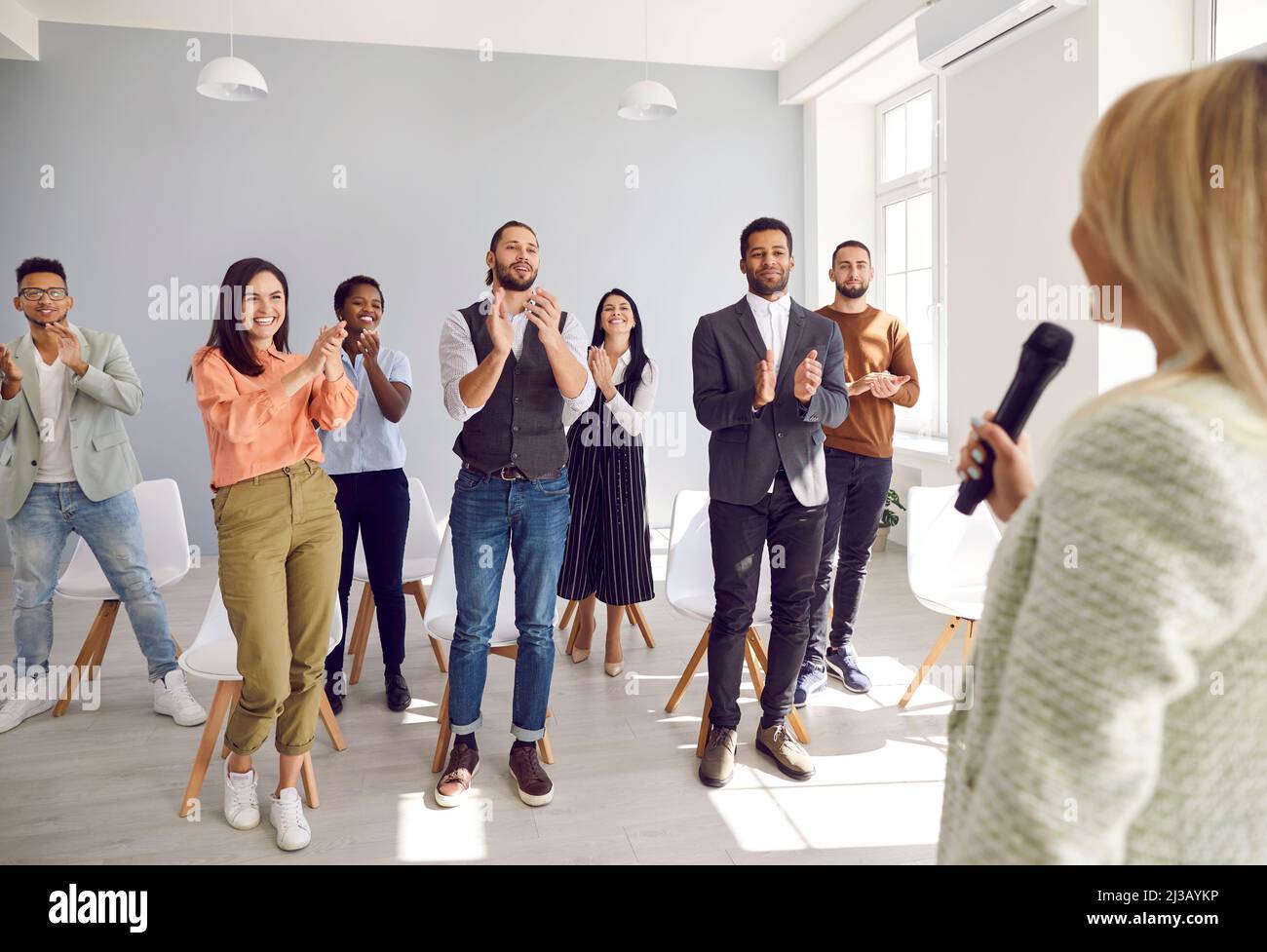 Glückliche, dankbare Menschen applaudieren Sprecherin, die mit ihnen seine Erfahrungen und sein Wissen teilte. Stockfoto