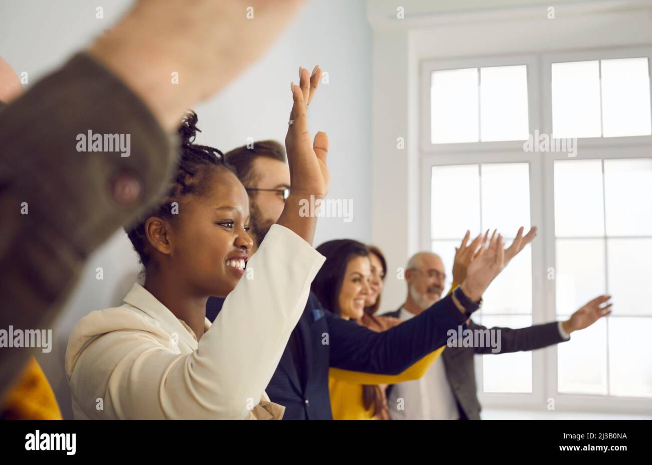 Glückliches, multirassisches Publikum, das bei einer Konferenz oder einem Seminar die Hände hochhebt und Fragen stellt Stockfoto Glückliches, multirassisches Publikum, das bei einer Konferenz oder einem Seminar die Hände hochhebt und Fragen stellt Stockfoto