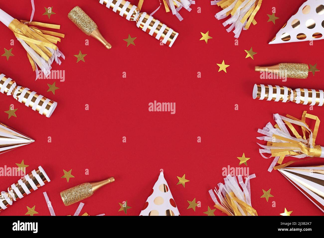 Goldene Party-Objekte wie Hüte, Konfetti und Geschenke bilden Rahmen um roten Hintergrund Stockfoto