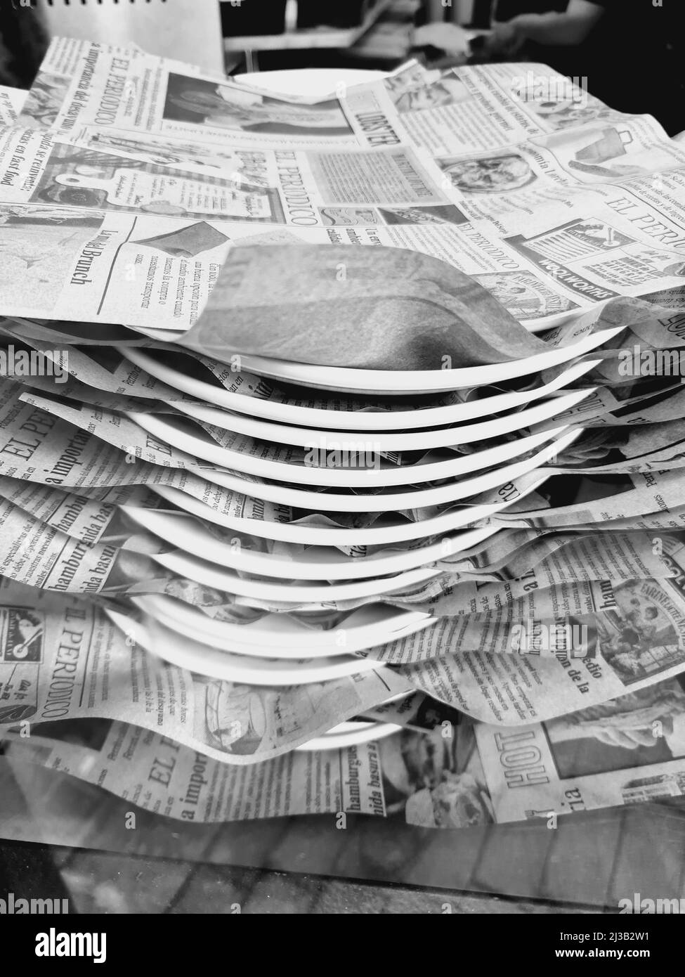 Teller mit Lebensmitteln mit Zeitungen auf der Oberseite, Schwarz-Weiß-Fotografie. Stockfoto