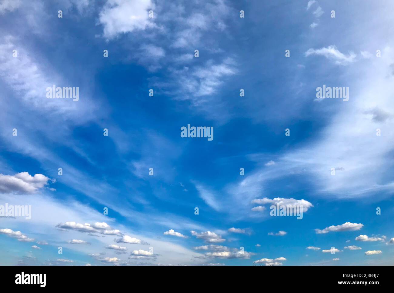 Fedrige und flauschige Wolken auf einem fedrigen und flauschigen Wolken auf einem Hintergrund des blauen Himmels. Hintergrund des blauen Himmels. Stockfoto