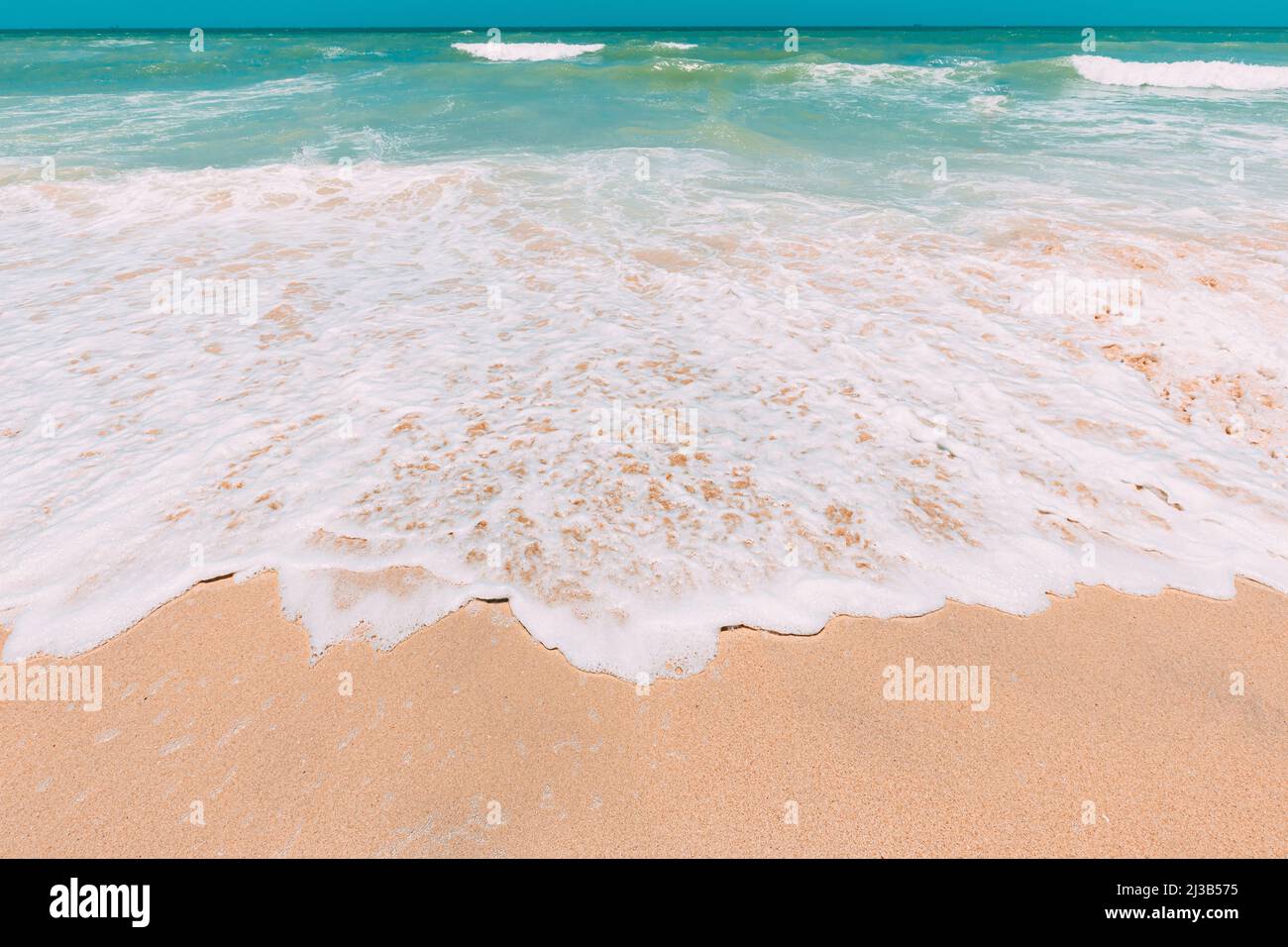 Meereswasser Schaum spritzt waschen Sandstrand. Atemberaubende Landschaftskulisse. Stürzende Wellen der sandigen Küste. Meeresoberfläche des Ozeans mit kleinen Wellen Stockfoto