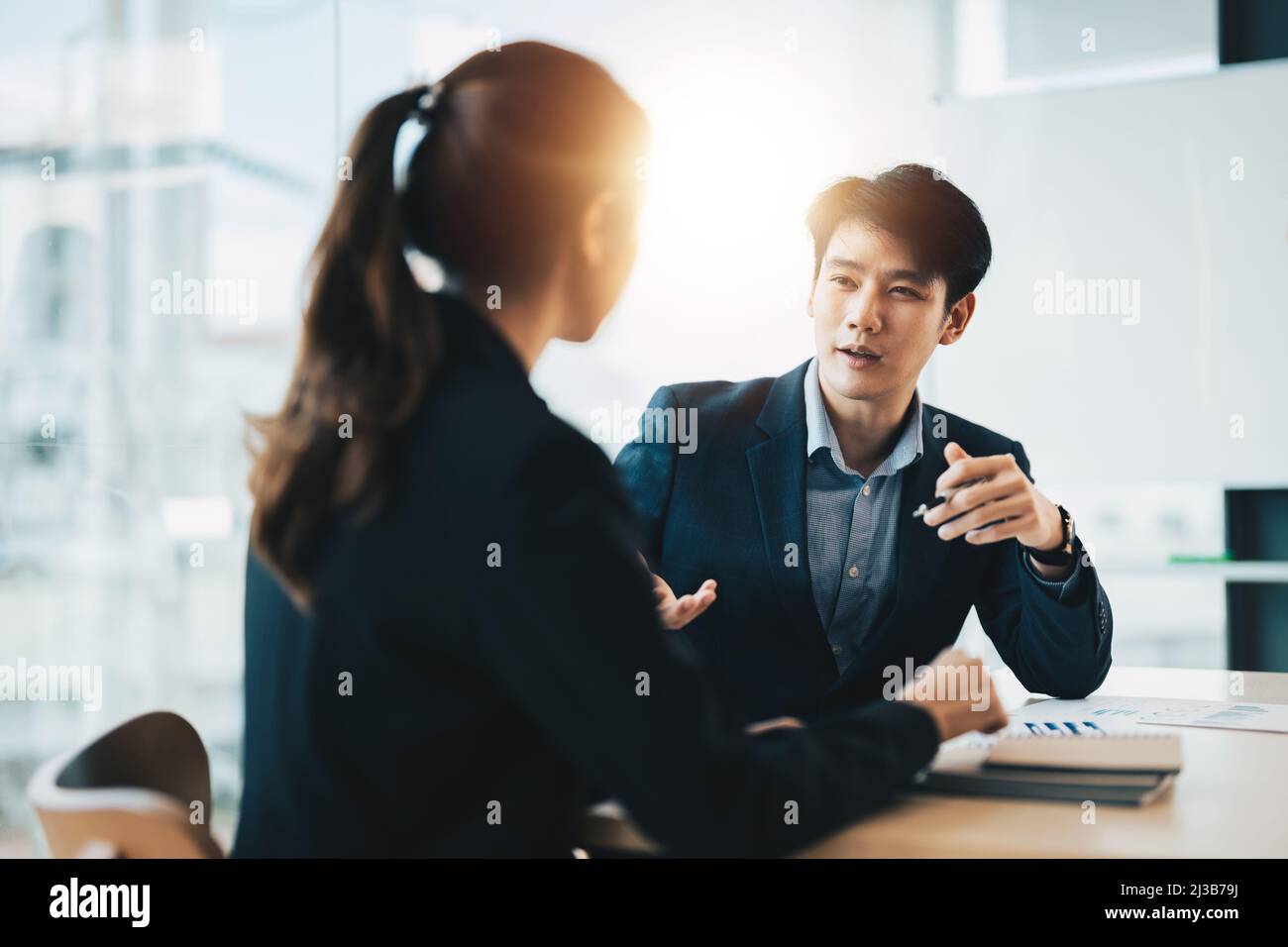 Zwei verschiedene asiatische Geschäftsleute, die diskutieren, arbeiten in einem Büro zusammen Stockfoto