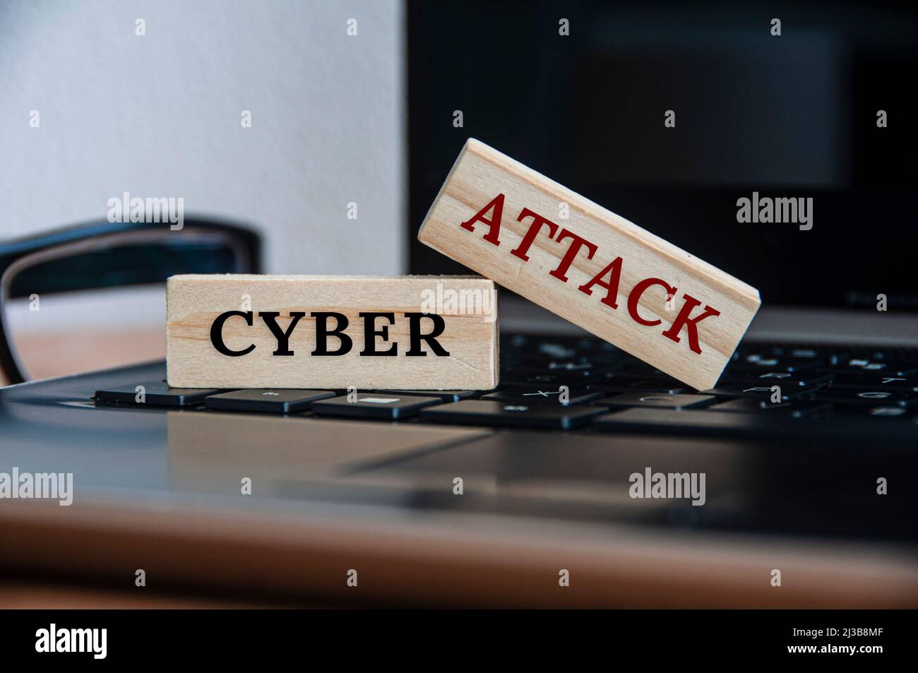 Cyberangriffstext auf Holzblöcken auf einem Laptop. Internet-Sicherheitskonzept Stockfoto