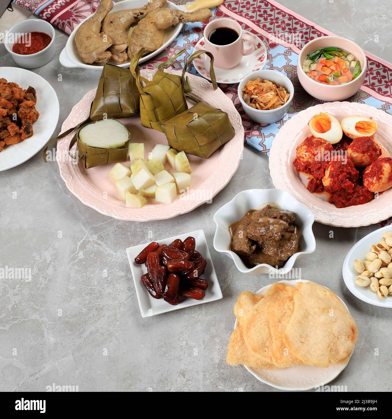 Ketupat Lebaran. Traditionelles festliches Gericht aus Reiskuchen oder Ketupat mit verschiedenen Beilagen, beliebt während der Eid-Feierlichkeiten. Stockfoto