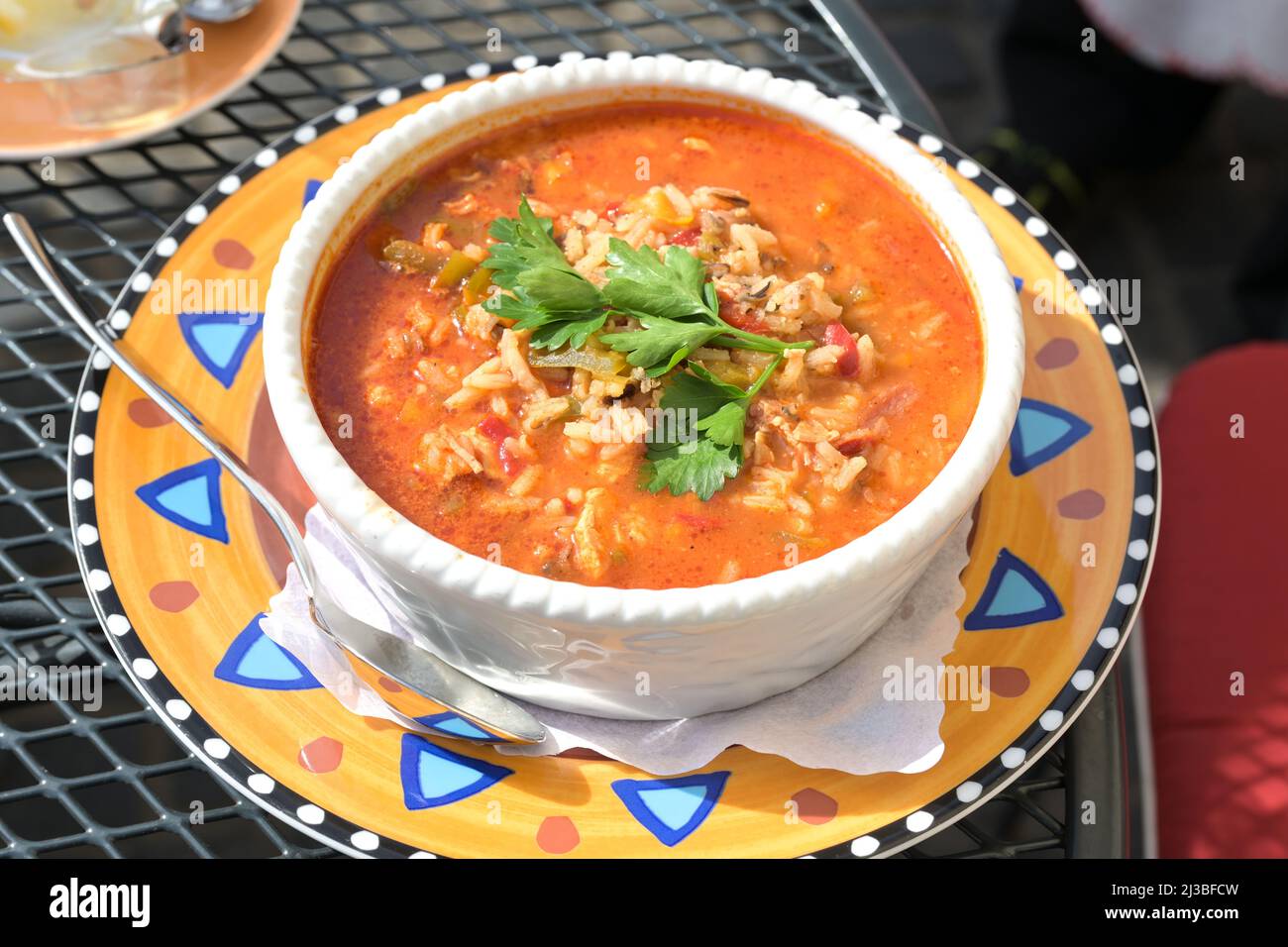 Ein-Topf-Jambalaya-Suppe mit Huhn, Garnelen, Wurst, Gemüse und Reis, kreolisches Gericht in einer Schüssel auf einem bunten Teller, ausgewählter Fokus Stockfoto