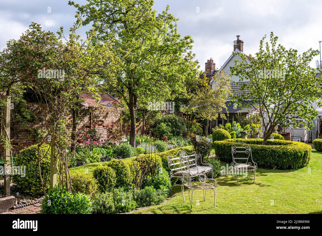 Gartenmöbel und Bäume im ummauerten Garten. Frühling in Suffolk, Englsnd, Großbritannien Stockfoto