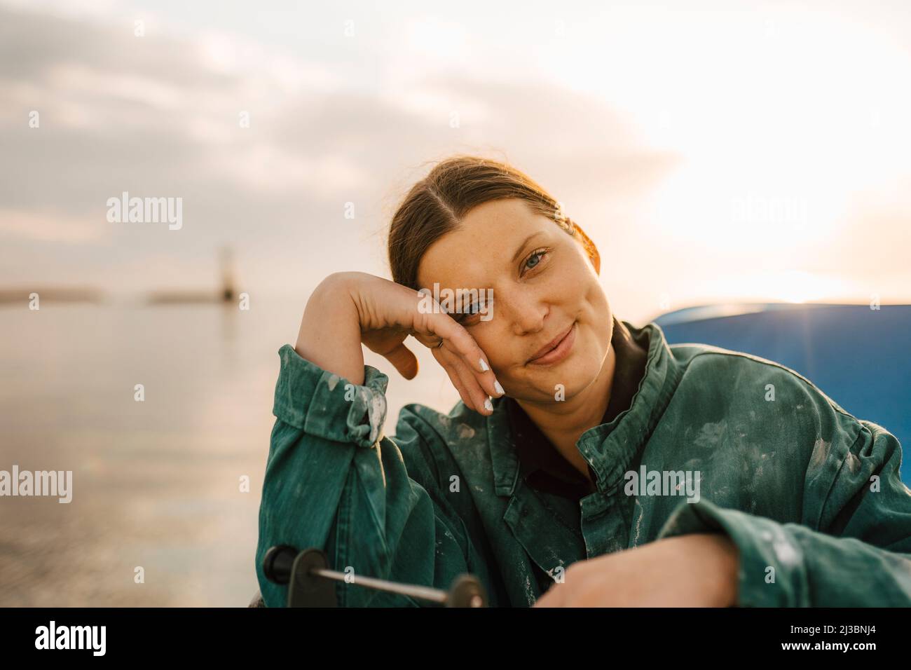 Porträt einer lächelnden Frau auf See bei Sonnenuntergang Stockfoto