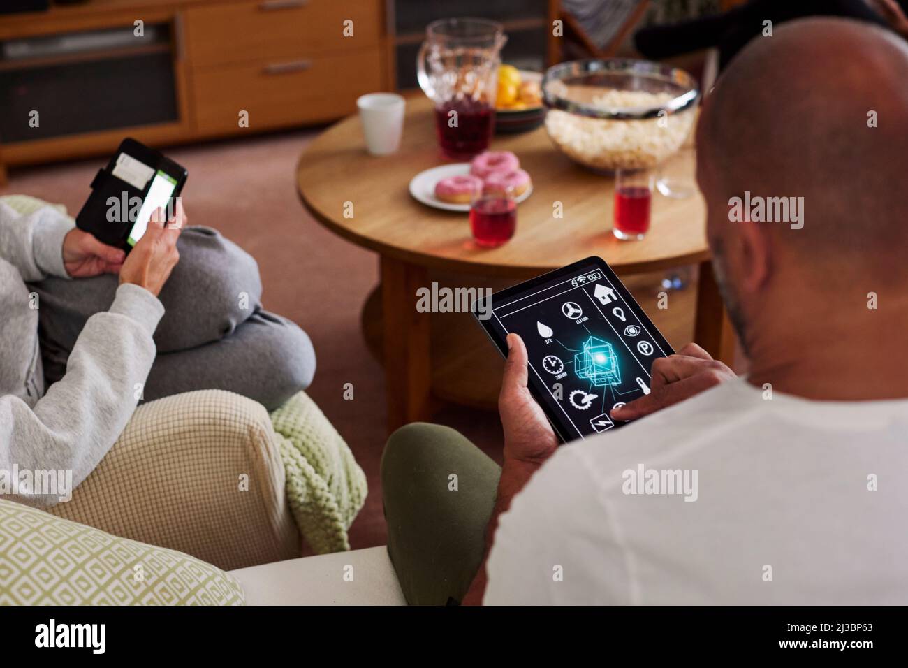 Familie entspannt im Wohnzimmer und mit Telefon und Tablet Stockfoto