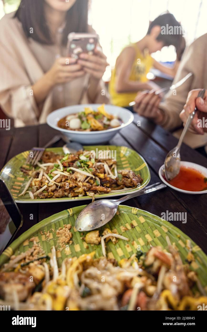 Leute essen asiatische Speisen am Tisch Stockfoto