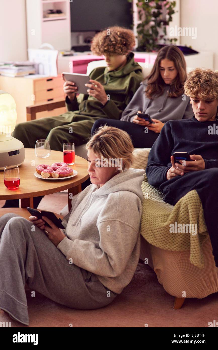 Mutter und Kinder, die zu Hause elektronische Geräte benutzen Stockfoto