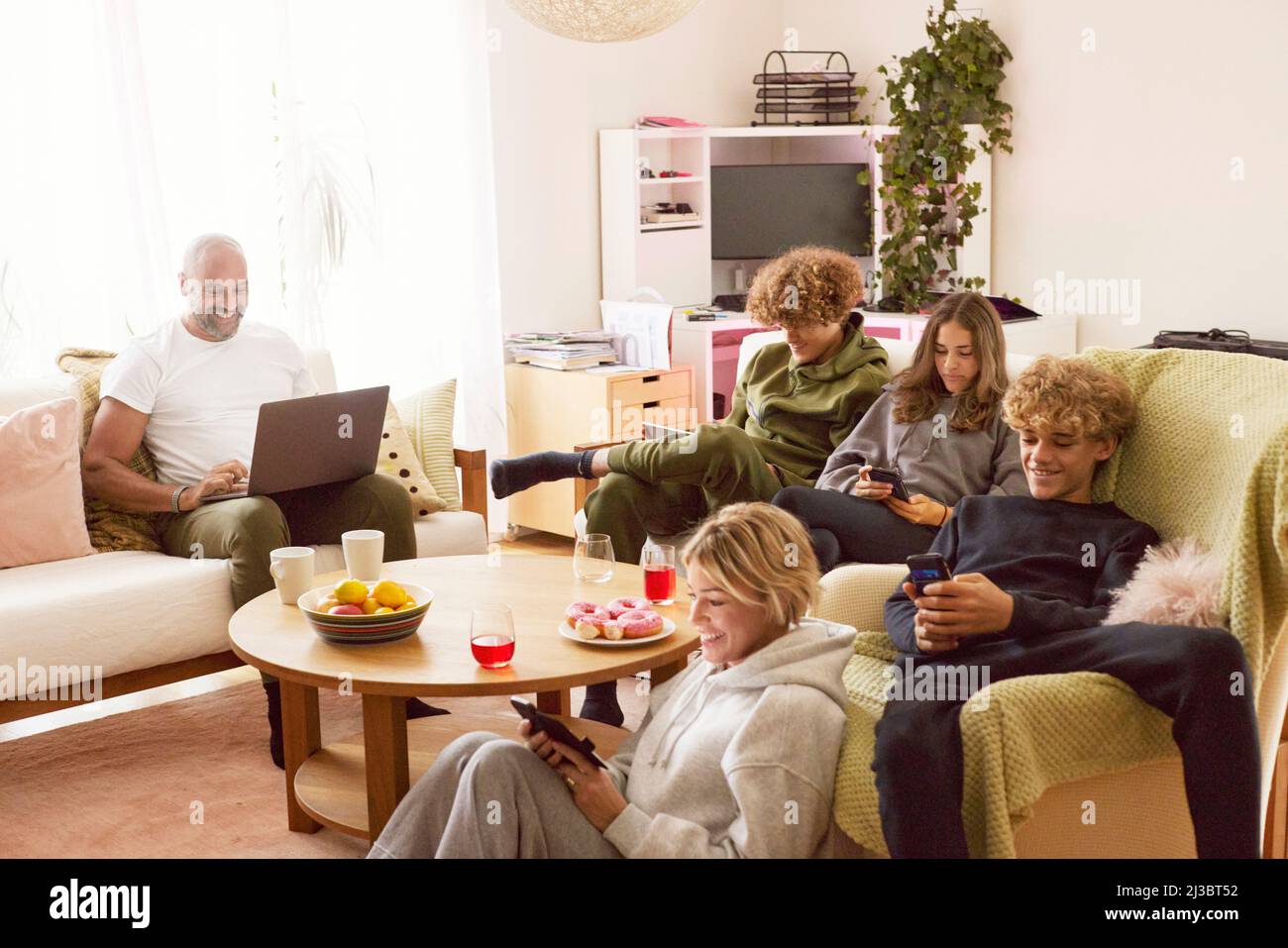 Familie mit Kindern, die zu Hause elektronische Geräte verwenden Stockfoto