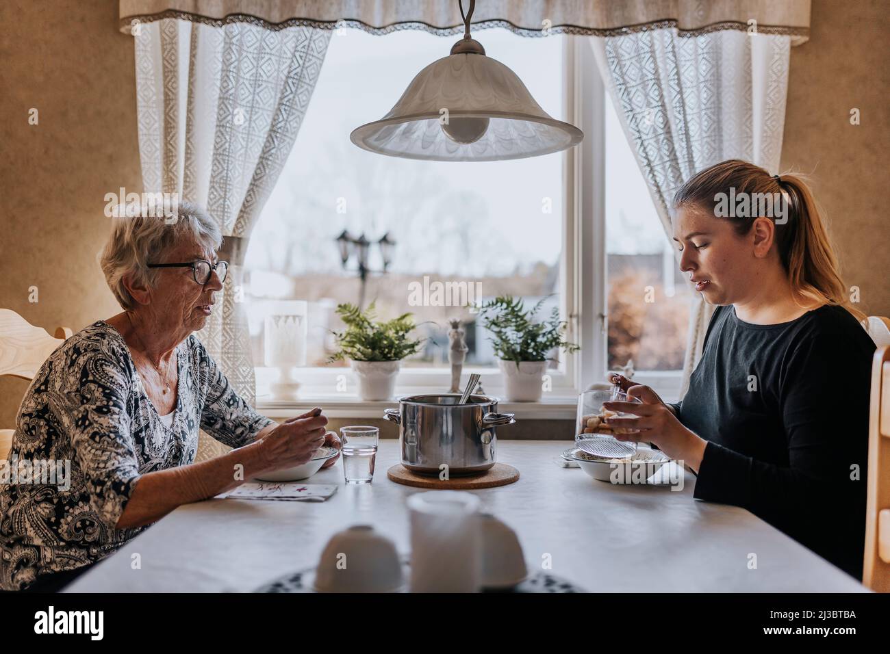 Großmutter und Erwachsene Enkelin essen zu Hause Stockfoto