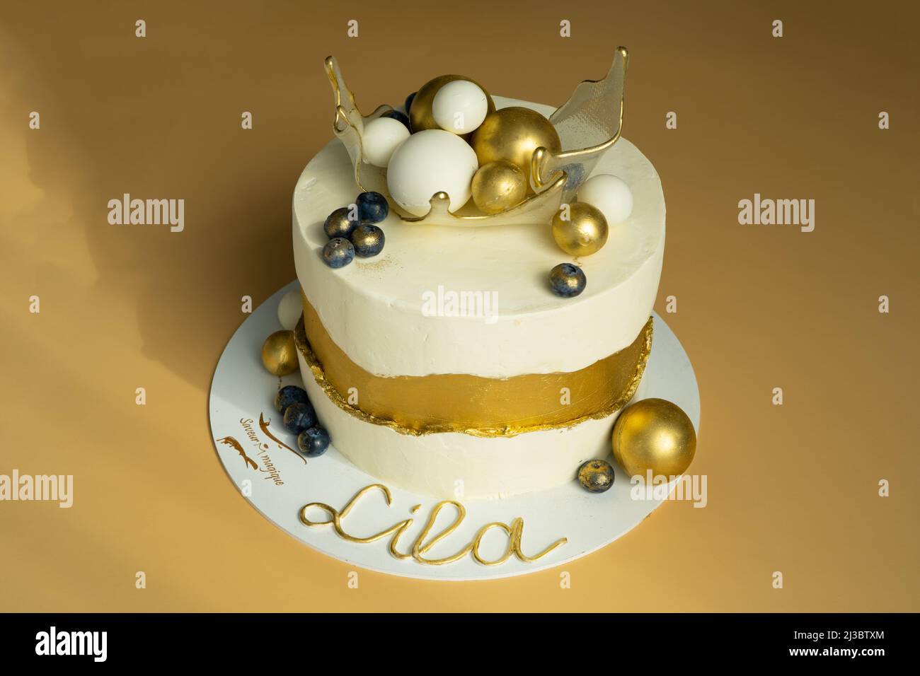 Eine schöne Geburtstagstorte, verziert mit Gold und Weiß mit Kugeln in einem karamellisierten transparenten Korb auf der Oberseite. Das Konzept der festlichen Desserts. Hochwertige Fotos Stockfoto