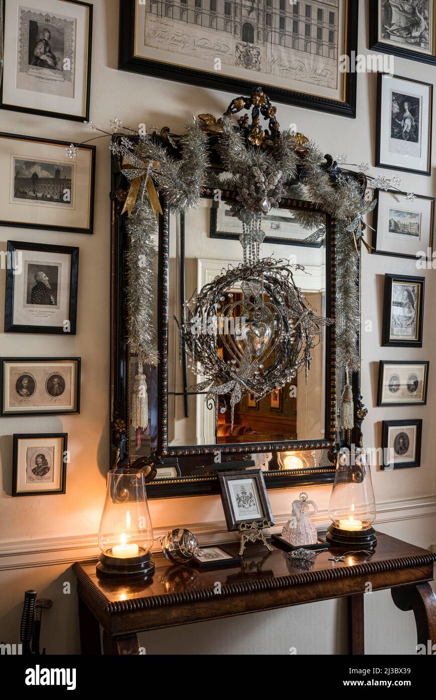 Gerahmte Drucke mit silbernem Lametta auf dem Spiegel in einem renovierten denkmalgeschützten Herrenhaus, Cambridgeshire, England, Großbritannien Stockfoto