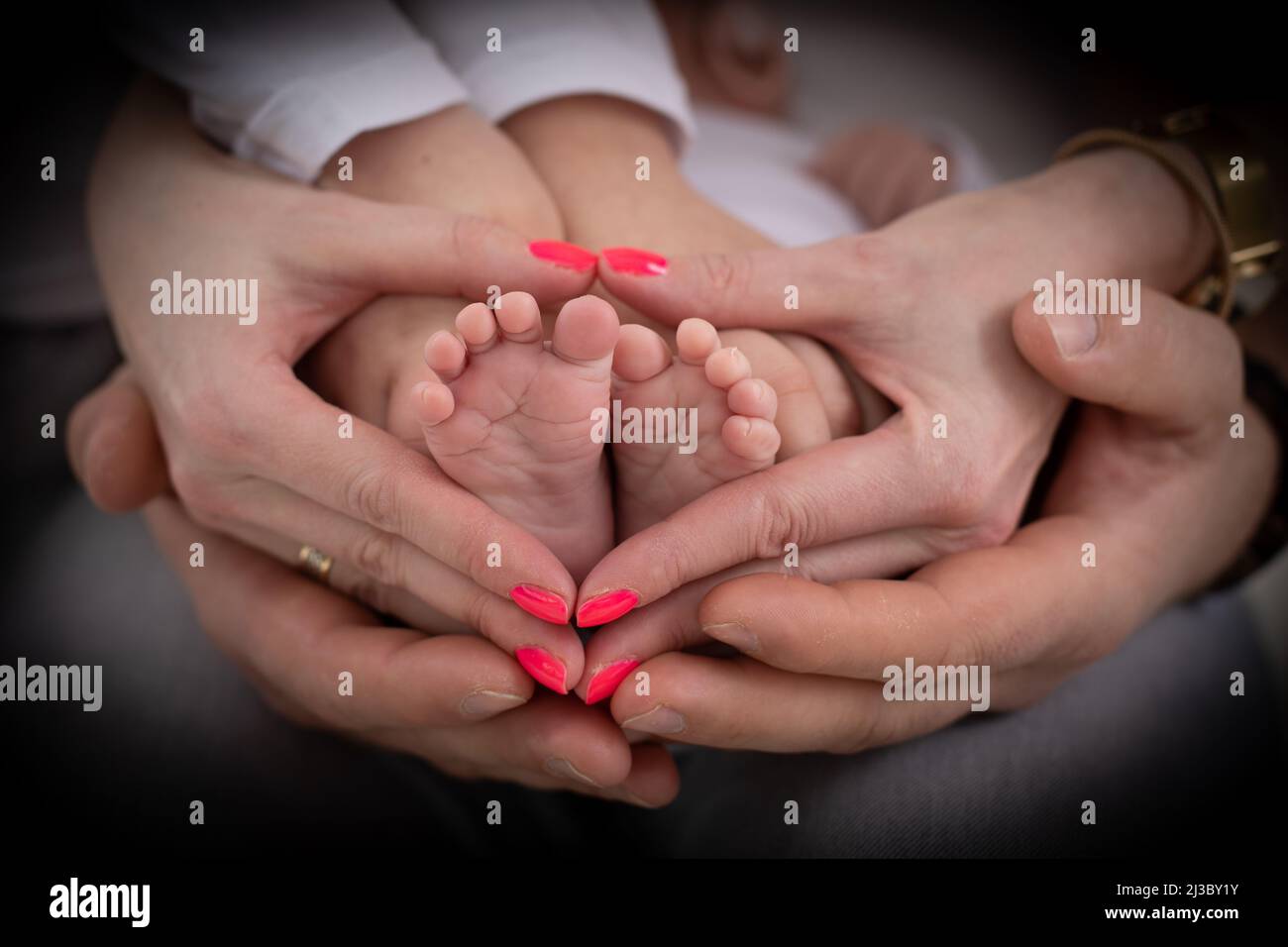 Junge unkenntliche Familie von Mutter Vater und Kind. Mama, Papa und Kind halten Beine, Fuß des neugeborenen Babys Stockfoto
