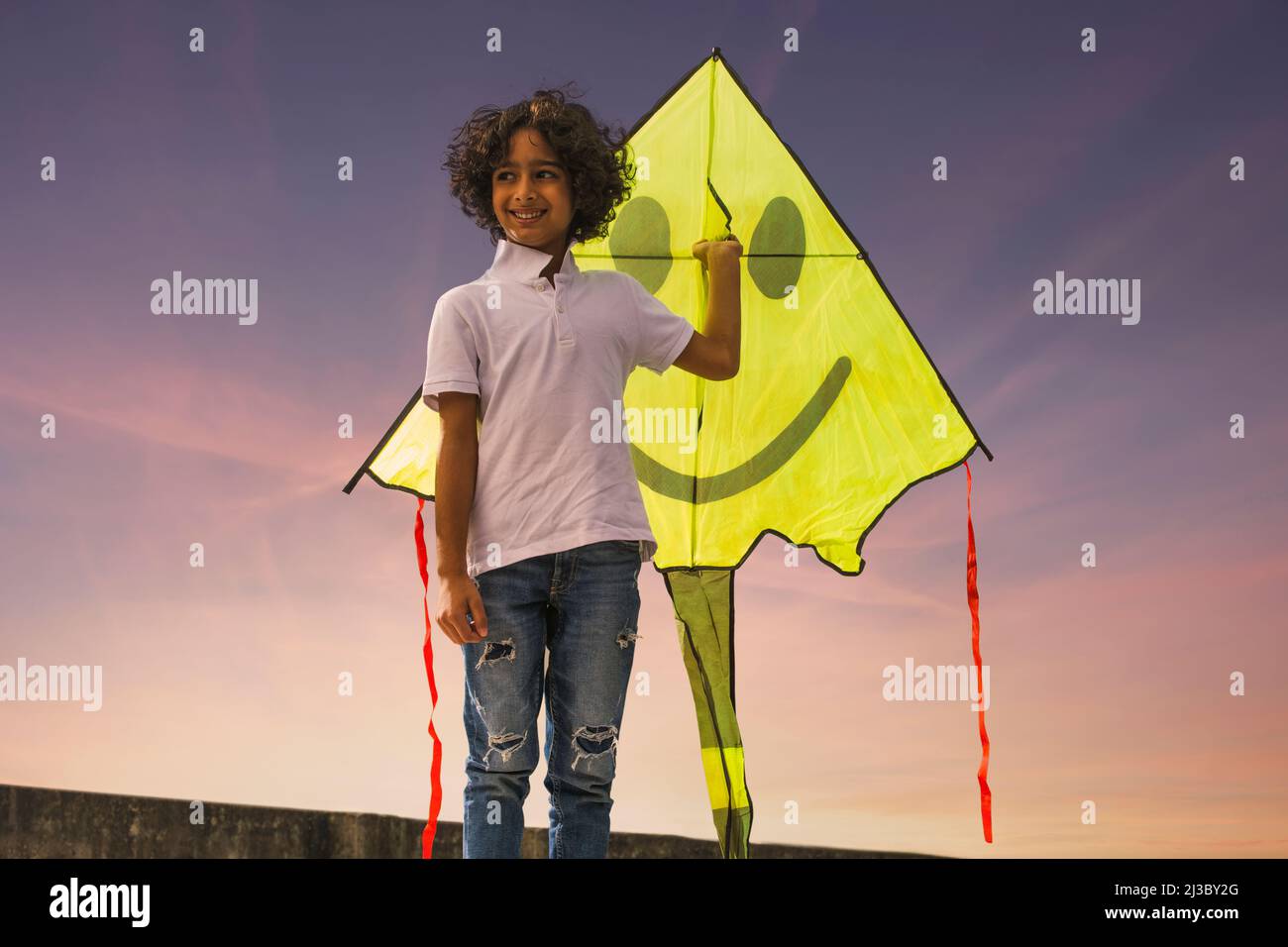 Junge, der auf der Dachterrasse steht und einen Drachen hält Stockfoto
