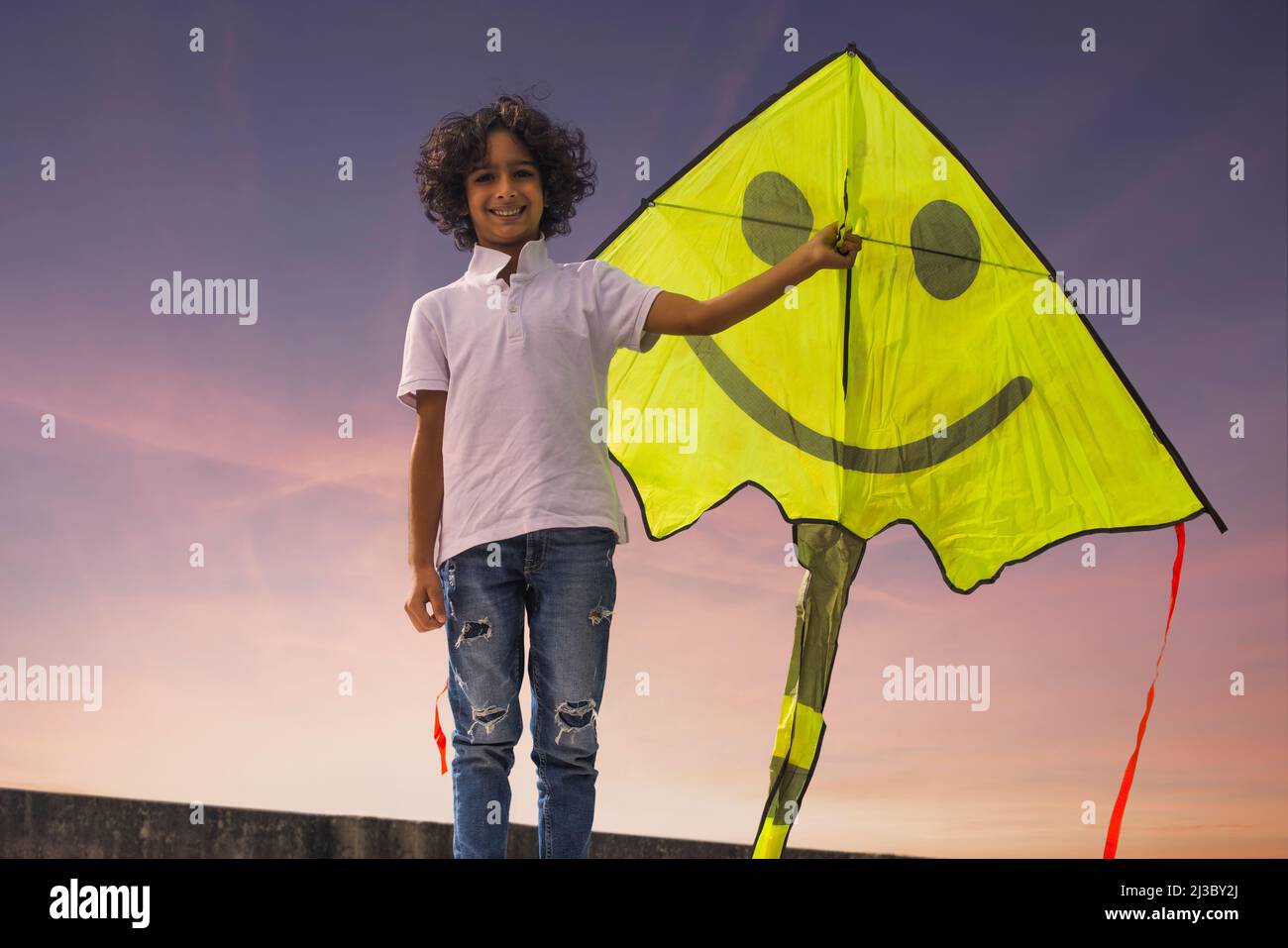 Junge, der auf der Dachterrasse steht und einen Drachen hält Stockfoto