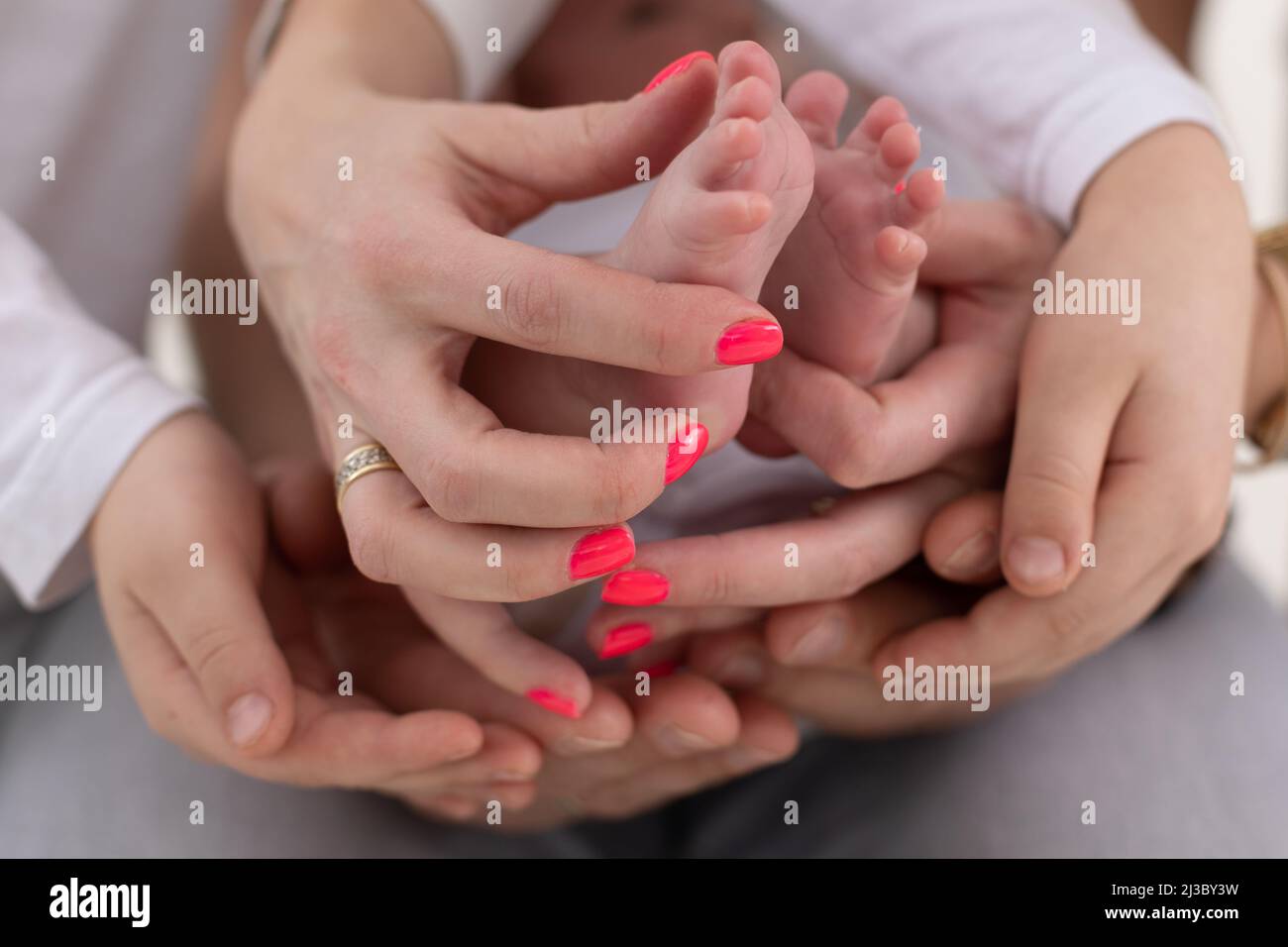 Nicht erkennbare Familie von Mutter Vater und Kind. Mutter, Vater, Kind halten Beine, Fuß der neugeborenen Baby-Familie mit zwei Kindern Stockfoto